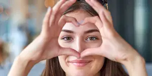 woman smiling and showing heart shape with her hands
