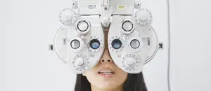 A woman is having her eyes examined with an ophthalmoscope