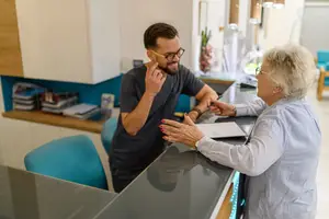 A man and an elderly woman are talking and shaking hands in a dental clinic.