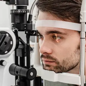 A man having his eyes checked with a slit lamp in an optometrist's office.