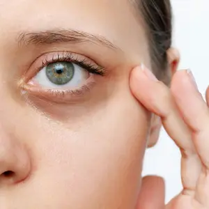 Close-up of a woman applying eye cream to her eye area.