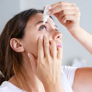 woman putting eye drops in her eye