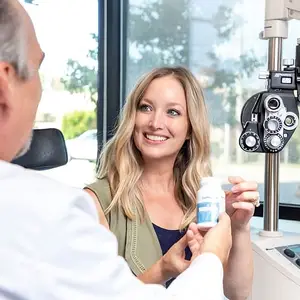 Woman in a medical office with a doctor holding a bottle of vitamins