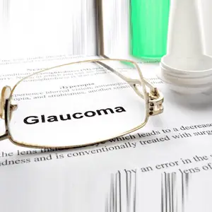 Close up of glasses and a bottle of eye drops on a piece of paper with the word Glaucoma