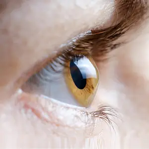 A close-up of a person's eye with long eyelashes and a slightly open eye.