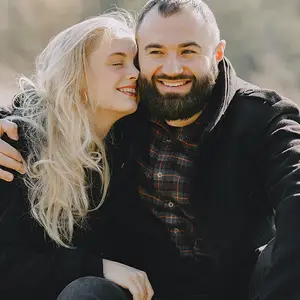 A man and a woman sitting in a park and smiling for the camera