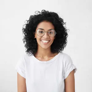 Portrait of a smiling woman with curly hair wearing a white shirt and glasses