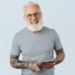 Older man with tattoos on his arms smiling while looking at his phone