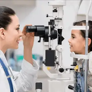 A doctor examining a young girl's eyes using an ophthalmoscope.