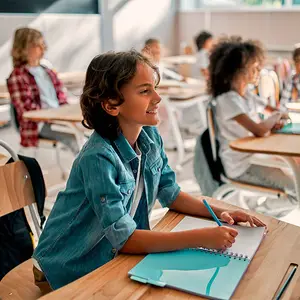 Girl sitting at desk in a classroom writing in a notebook