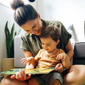 A woman reads a book to a baby on her lap.