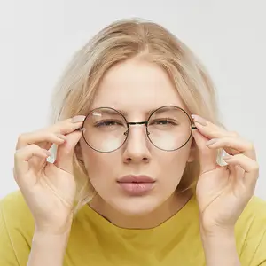 Blonde woman wearing yellow shirt and round glasses adjusting her glasses