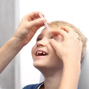 A boy getting eye drops administered by a person