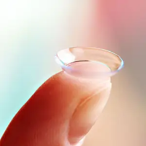 Close-up of a finger holding a transparent contact lens.