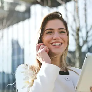 A smiling woman holding a tablet and talking on the phone