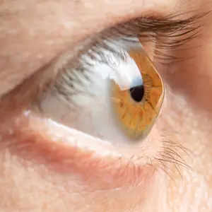 Close up of a person's eye with a slightly open eyelid showing the iris and pupil.