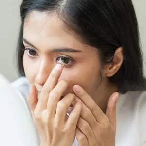 A woman examining a contact lens in her hand