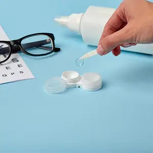 A person wearing glasses is using a white solution to clean a contact lens.
