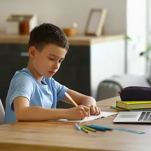 Boy sitting at a table writing on a piece of paper