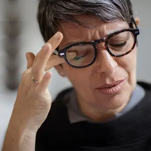Close up of a woman wearing glasses and adjusting them with her finger and thumb