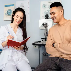 A woman doctor and a man patient smiling at each other inside a clinic