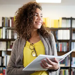 A woman in a library with books and shelves in the background