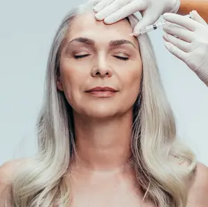 A woman with gray hair getting a facial injection in a studio