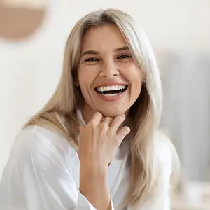Blonde woman smiling and showing her teeth in a white shirt