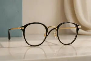 A pair of glasses with black frames and gold accents sitting on a white surface