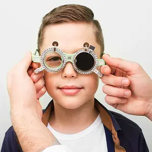Young boy getting his eyes examined wearing green trial frame glasses