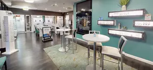 An interior of an optical shop with tables, chairs, and shelves of glasses for sale