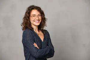 Woman smiling with curly hair and eyeglasses posing for a photo
