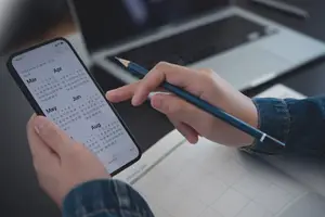 Person holding pencil and checking calendar to schedule an eye exam.