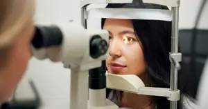 Woman undergoing slit-lamp eye examination for disease detection.