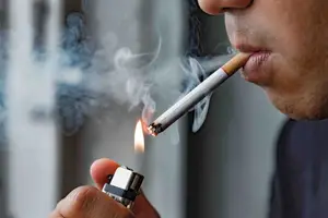 Person lighting a cigarette, illustrating smoking as a risk for eye disease.