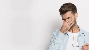 A man with brown hair and beard wearing a light blue shirt and holding a pair of glasses in his hand while covering his face with his hand, looking down. Marion, Cedar Bluff, Bristol, Abingdon, and Gray