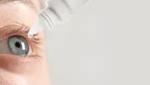 Woman applying eye drops to her eye