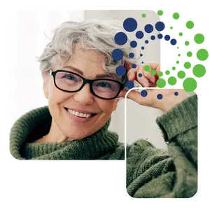 A smiling elderly woman wearing glasses and a green sweater.