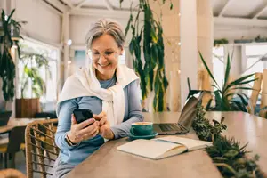 Woman sitting in a cafe using her phone and smiling