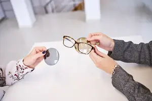 Two people examining eyeglasses in a shop.