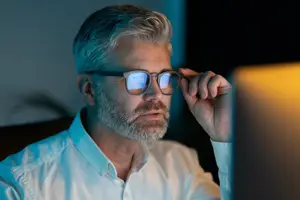 business man adjusting glasses in a dimly lit room