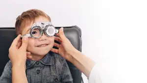 A young boy is having his eyes examined by an optometrist in a clinic setting