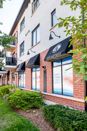 Exterior view of an optometrist office building with brick walls, black awnings, and large windows displaying custom contact lens fitting services.