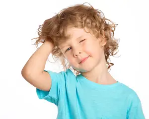 A little boy with curly blonde hair wearing a blue t-shirt posing for a photo
