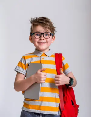 A young boy wearing a striped shirt is holding a tablet and giving a thumbs up with a smile