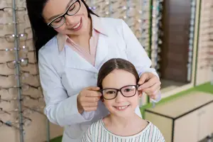 Optician helping a young girl with her glasses in a store