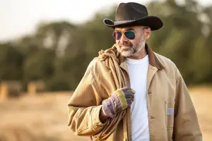 A man in a hat and sunglasses is holding a rope in his left hand and looking forward