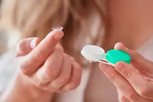 Woman holding a contact lens and its container