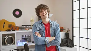 Young man standing in a music studio room with a smile on his face
