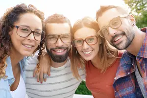 Four smiling people wearing glasses in a garden